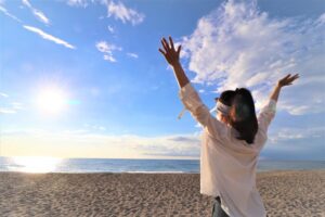 太陽に向かって万歳をする女性の写真